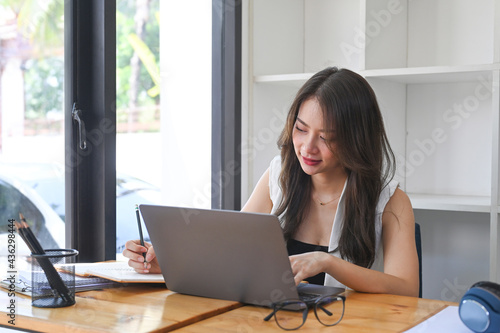 Happy young female freelancer working online with laptop computer.