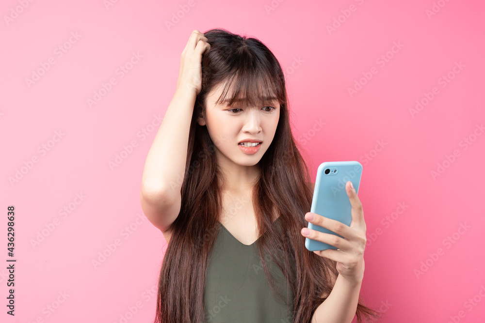 Beautiful young asian girl using phone on pink background Beautiful young asian girl using phone on pink background