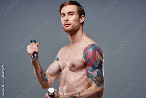 sexy athlete with pumped up arm muscles and health vitamins dumbbells model