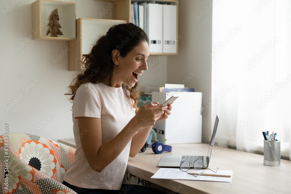 Emotional happy young hispanic woman looking at cellphone screen, feeling excited of getting amazing news, celebrating online lottery betting gambling win or received shopping sale promo code. Emotional happy young hispanic woman looking at cellphone screen, feeling excited of getting amazing news, celebrating online lottery betting gambling win or received shopping sale promo code.