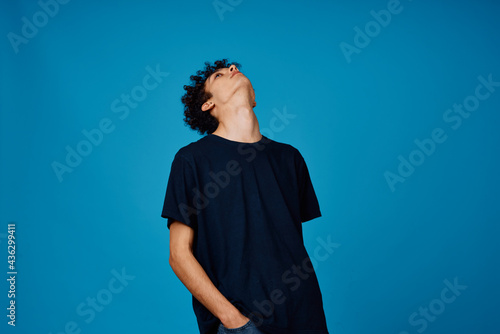 guy in black t-shirt with curly hair blue background