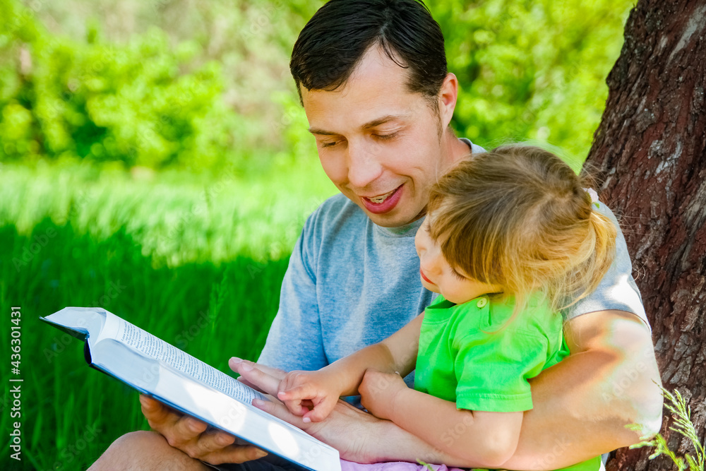 happy father with a child reading a book on the nature of the Bible happy father with a child reading a book on the nature of the Bible