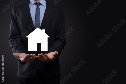 Businessman male hand holding house icon on blue background. Property insurance and security concept.Real estate concept.Banner with copy space.