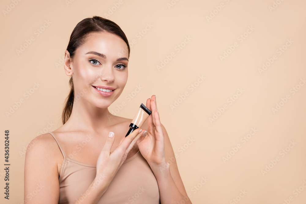 Fototapeta premium pretty woman with natural makeup holding concealer isolated on beige.