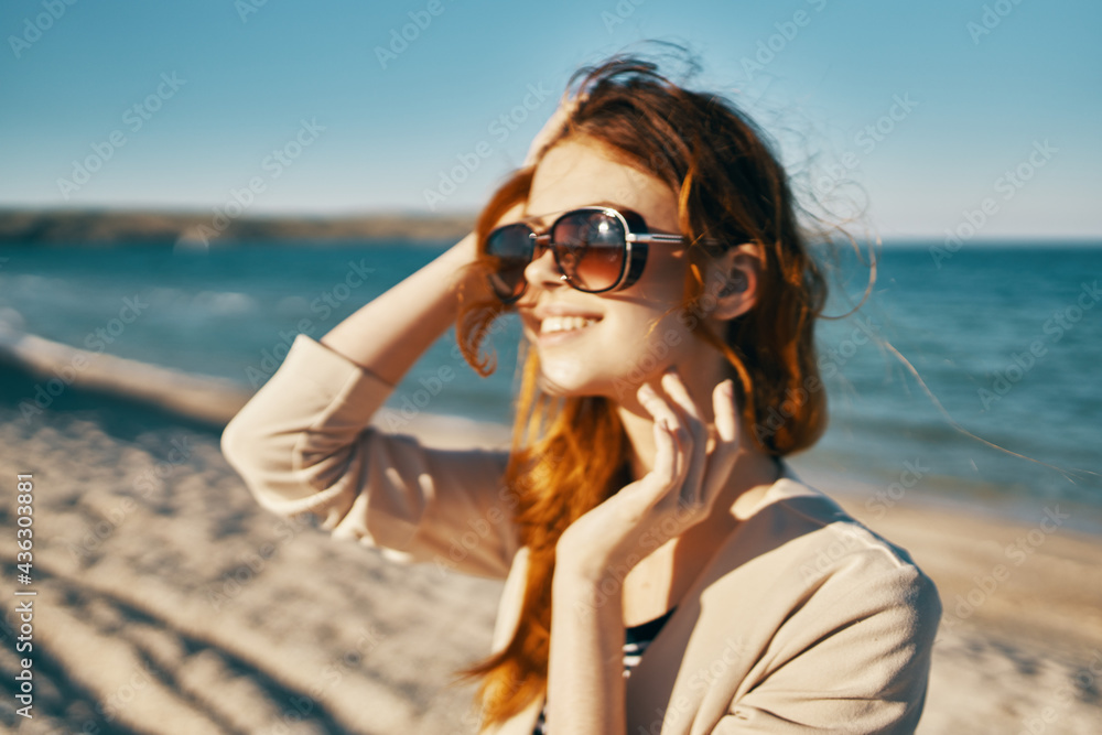 woman in sunglasses in summer looks to the side near the sea in the mountains summer