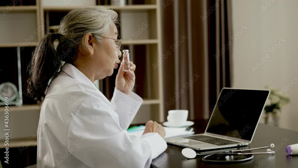 Senior Female Doctor video calling distant patient on laptop computer Senior Female Doctor video calling distant patient on laptop computer