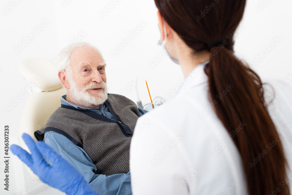Obraz premium senior patient in dental chair taking consultation from doctor in clinic.