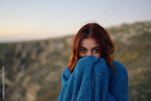 pretty woman in the mountains outdoors covered herself with a blanket coolness traveling