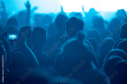 Silhouette of concert crowd at music festival in blue stage lights