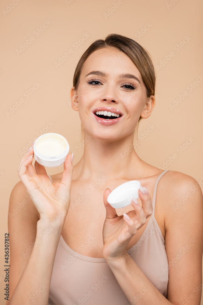 happy woman with cosmetic cream smiling at camera isolated on beige. happy woman with cosmetic cream smiling at camera isolated on beige.