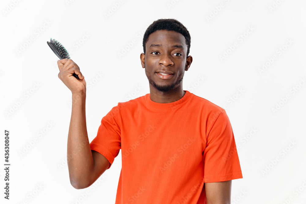 man of african appearance t-shirt with a comb in his hands head care light background man of african appearance t-shirt with a comb in his hands head care light background