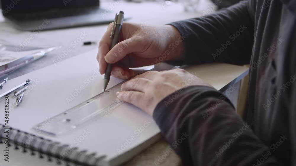 Adult carefully measures and draws straight line on paper with ruler, 4k