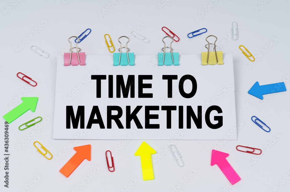 On the table there are paper clips and directional arrows, a sign that says - TIME TO MARKETING On the table there are paper clips and directional arrows, a sign that says - TIME TO MARKETING