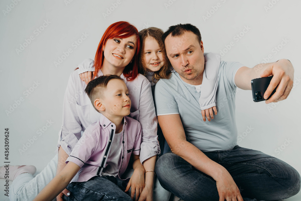 Selfie time. Joyful well-built man smiles and takes a selfie with his family against a white background.