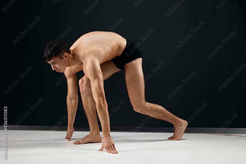 handsome male bodybuilder in black shorts on a dark background