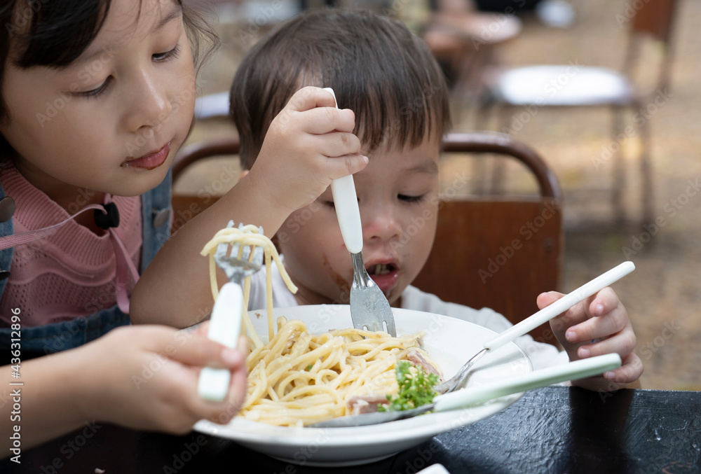 Asian boys and girls are eating spaghetti with deliciousness. Sister and brother are eating spaghetti Asian boys and girls are eating spaghetti with deliciousness. Sister and brother are eating spaghetti