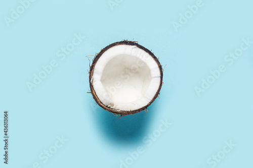 split half of a coconut on a blue background. Top view, flat lay