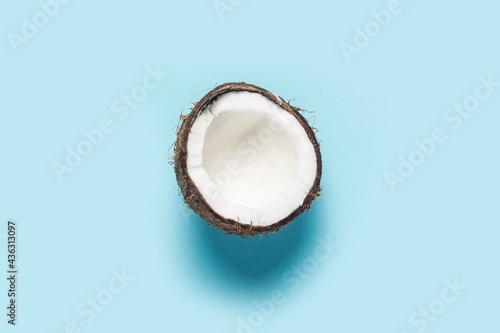 open half of a coconut on a blue background. Top view, flat lay