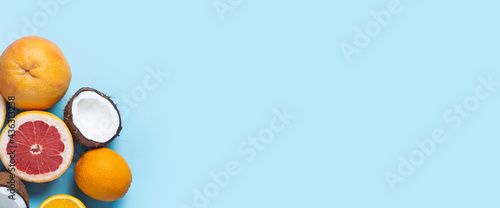 exotic fruits on a blue background. Coconut, orange, grapefruit. Top view, flat lay. Banner