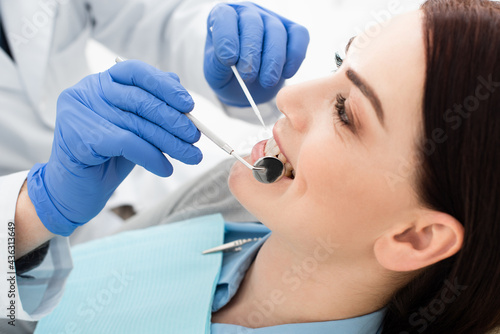 close up view of adult woman having teeth examination by doctor in latex gloves in clinic.