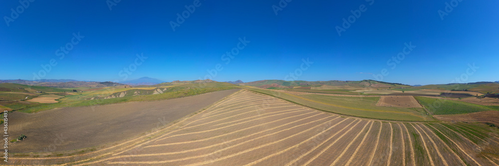 Fototapeta premium 180 degree saerial photo of the wheat fields in the heart of Sicily in the Erei mountains. Sicilian wheat cultivation. Small rural villages of Ramacca and Raddusa. Hay and grain. Etna view.