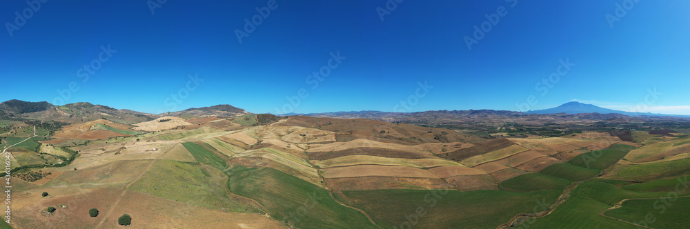 180 degree saerial photo of the wheat fields in the heart of Sicily in the Erei mountains. Sicilian wheat cultivation. Small rural villages of Ramacca and Raddusa. Hay and grain. Etna view.