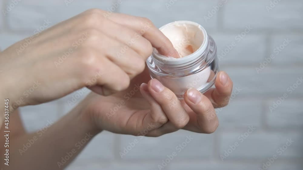 Moistened cream for face. A lady use moisturizing cream for her face in the room. A concept of domestic skin care. Moistened cream for face. A lady use moisturizing cream for her face in the room. A concept of domestic skin care.