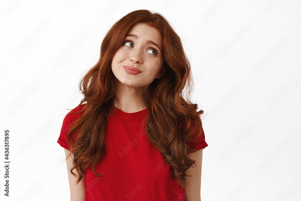 Indecisive cute redhead woman looking aside, avoid eye contact and shrugging unsure, hesitating, standing coy in t-shirt against white background Indecisive cute redhead woman looking aside, avoid eye contact and shrugging unsure, hesitating, standing coy in t-shirt against white background