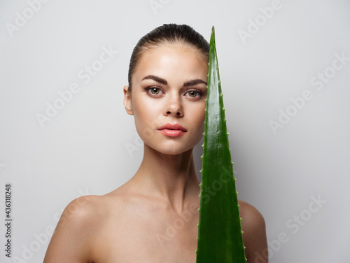 a woman with bare shoulders holds in her hand a green leafy 