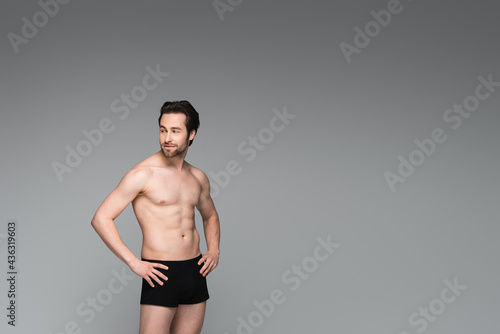 shirtless man in black underwear posing with hands on hips isolated on grey.