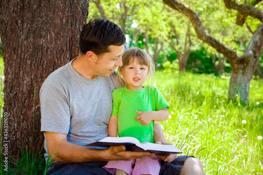 happy father with a child reading a book on the nature of the Bible happy father with a child reading a book on the nature of the Bible