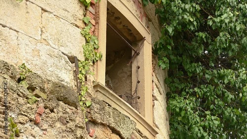 Handheld establishment shot of abandoned castle in Slovenia. Low angle view of ancient round tower with broken windows. Middle age ruins. Bushes sway in breeze. Real time, wide angle photo