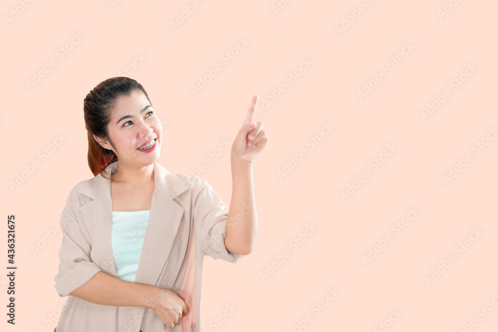 A young Asian woman standing, pointing the index finger of her left hand upward with a smiling face. A young Asian woman standing, pointing the index finger of her left hand upward with a smiling face.