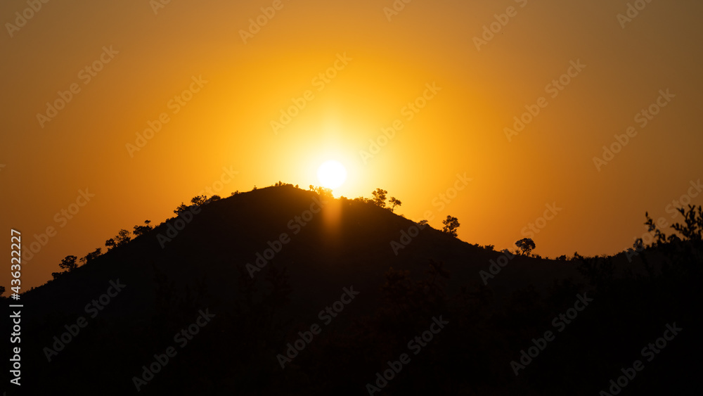 Fototapeta premium sun setting behind a mountain