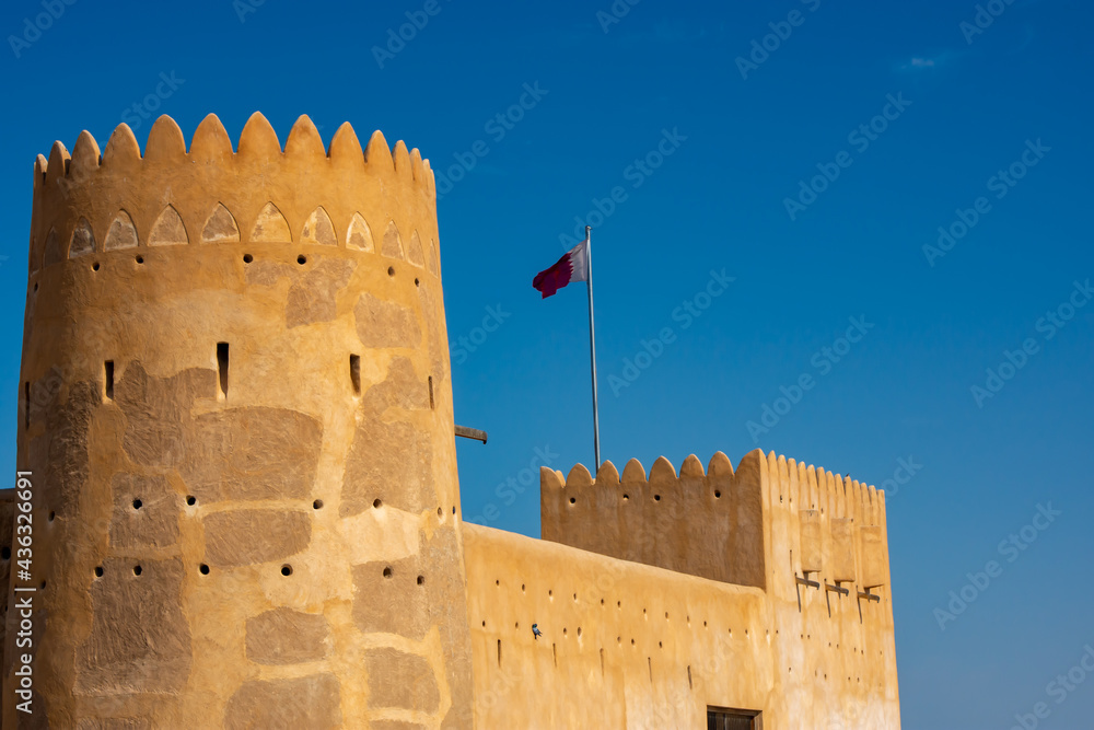 Exterior view of of Al Zubarah Fort with the Qatar flag flying from a tower. Exterior view of of Al Zubarah Fort with the Qatar flag flying from a tower.