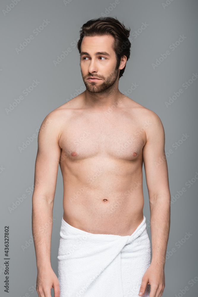 young muscular man in towel looking away isolated on grey.
