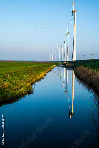 Line of windmills reflecting on a channel of water.... photo
