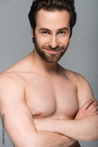 good-looking shirtless man smiling and posing with crossed arms isolated on grey.