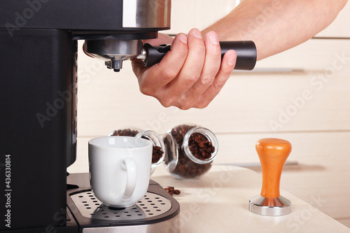 Coffeemaker hands inserts holder into coffee machine to make coffee.