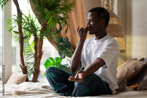 Canvas Print Young african man practicing yoga lesson, doing Alternate Nostril Breathing exer