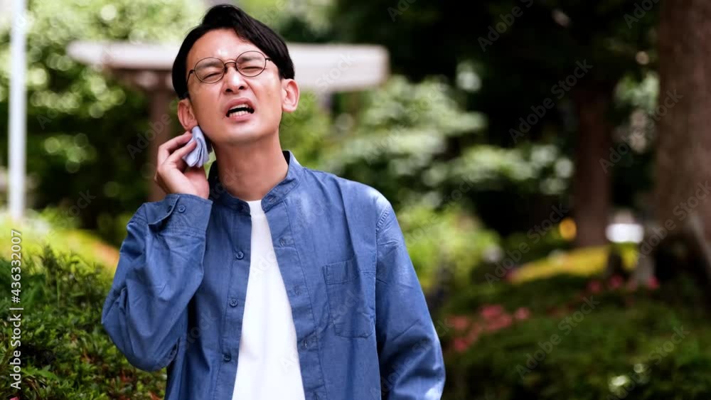 日差しを熱いと感じる青いシャツの男性