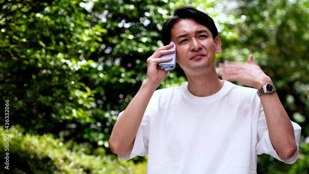 日差しを熱いと感じる白いシャツの男性 日差しを熱いと感じる白いシャツの男性