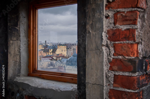 Panorama of the roofs of the old city. View of the city through the attic window. Cloudy weather.