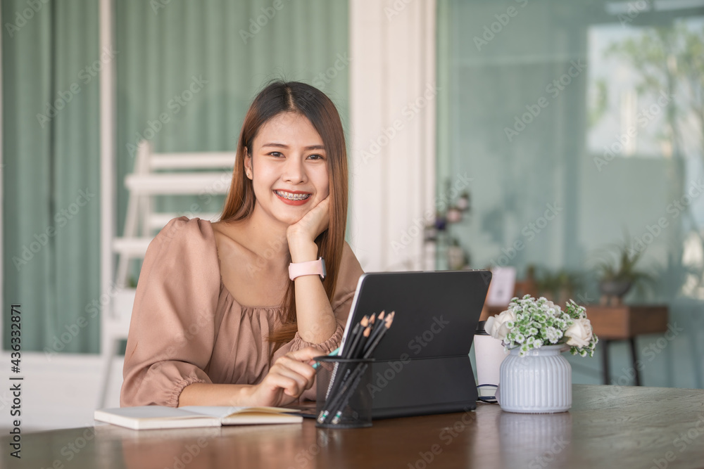 Portrait of a female entrepreneur looking into the camera while working with a computer in an office room.. Portrait of a female entrepreneur looking into the camera while working with a computer in an office room..
