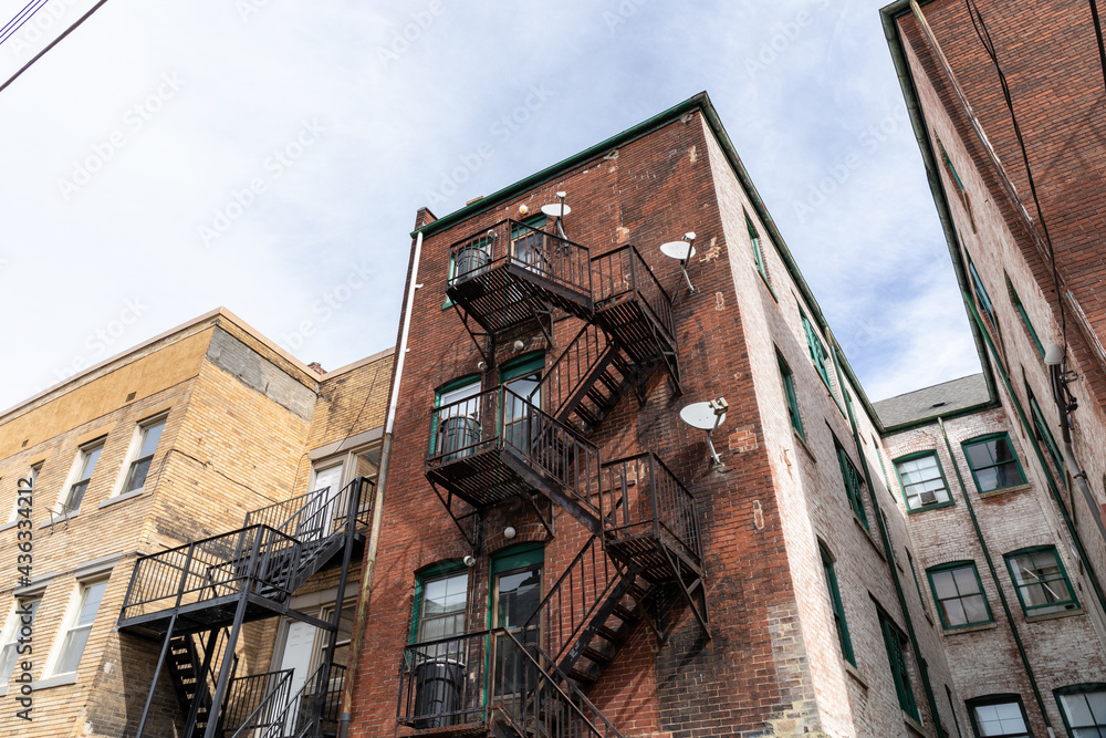 Rear view of old brick apartment buildings with metal fire escapes, windows and doors, horizontal aspect