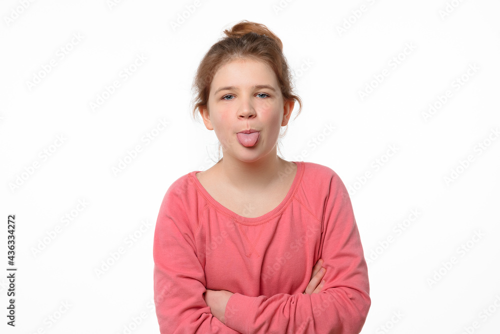 Portrait of offended young girl holding hands crossed and showing tongue, looking at camera Portrait of offended young girl holding hands crossed and showing tongue, looking at camera
