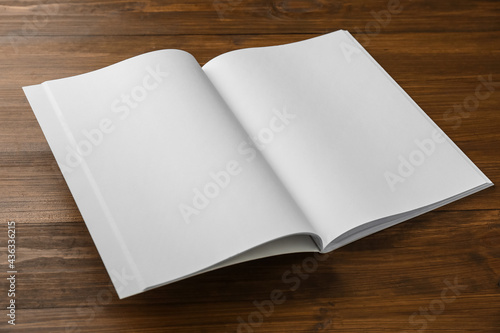 Open blank paper brochure on wooden table. Mockup for design