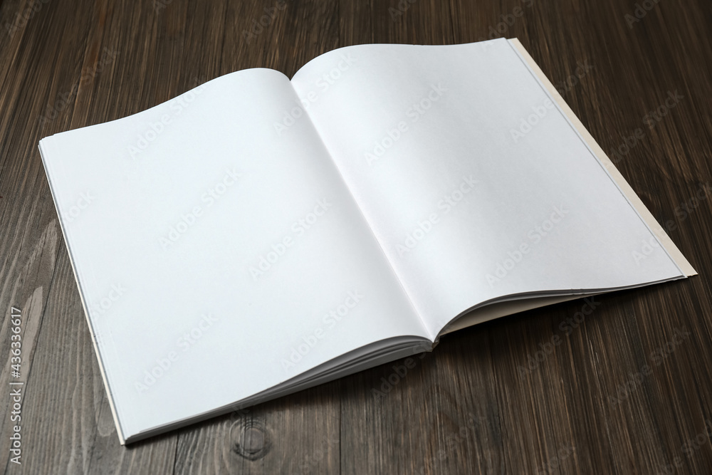 Fototapeta premium Open blank paper brochure on wooden table. Mockup for design