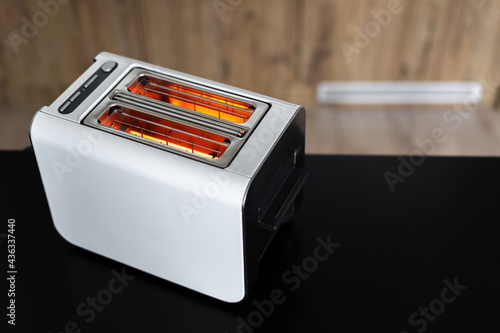 Modern white heated toaster on black table