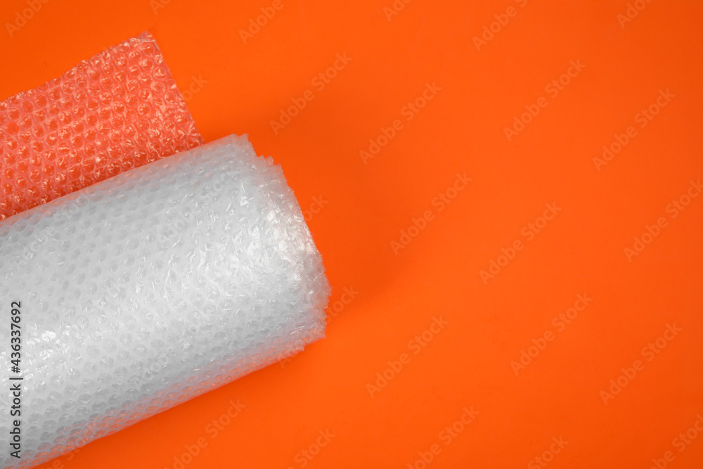 Obraz premium Bubble wrap roll on orange background, top view. Space for text
